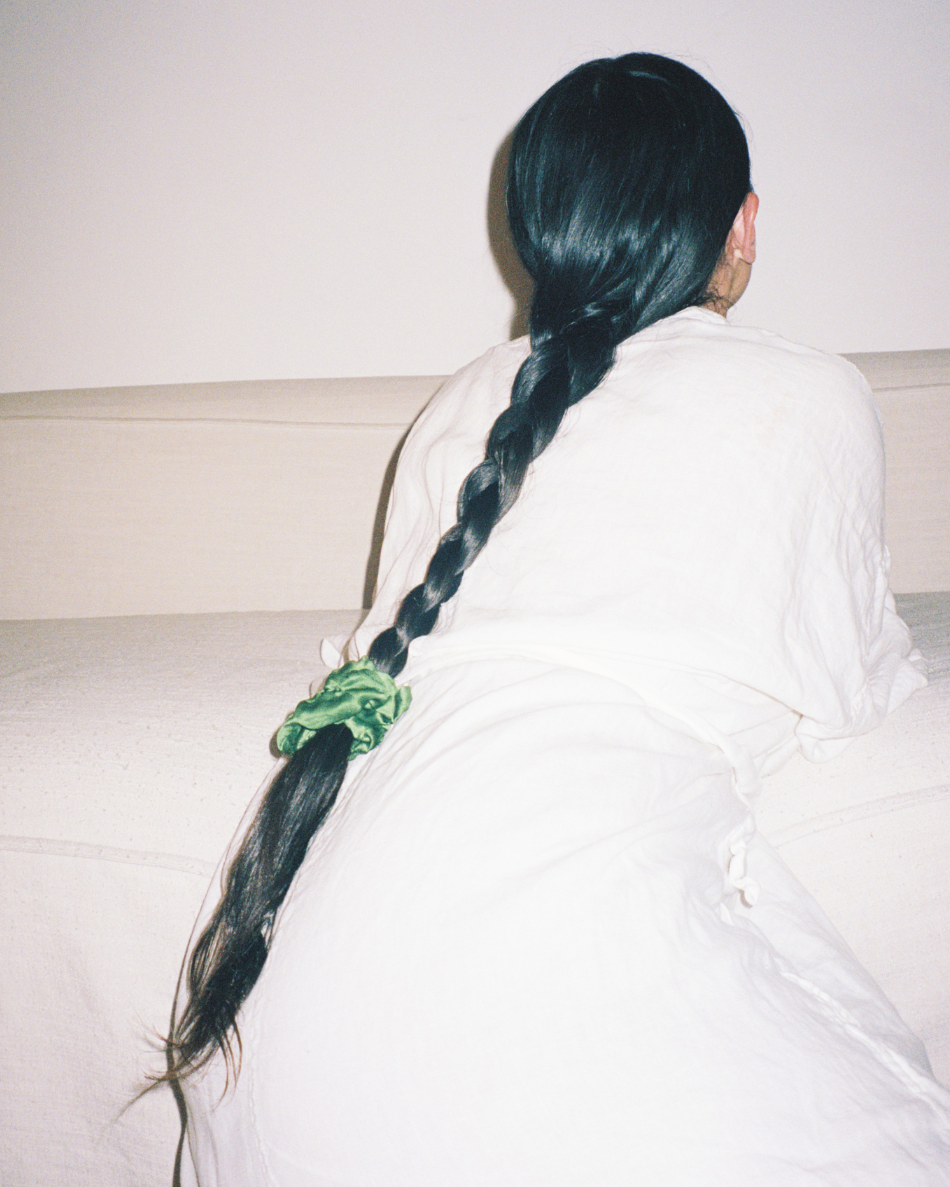 Rear view of a woman with a long braid secured by a green silk scrunchie