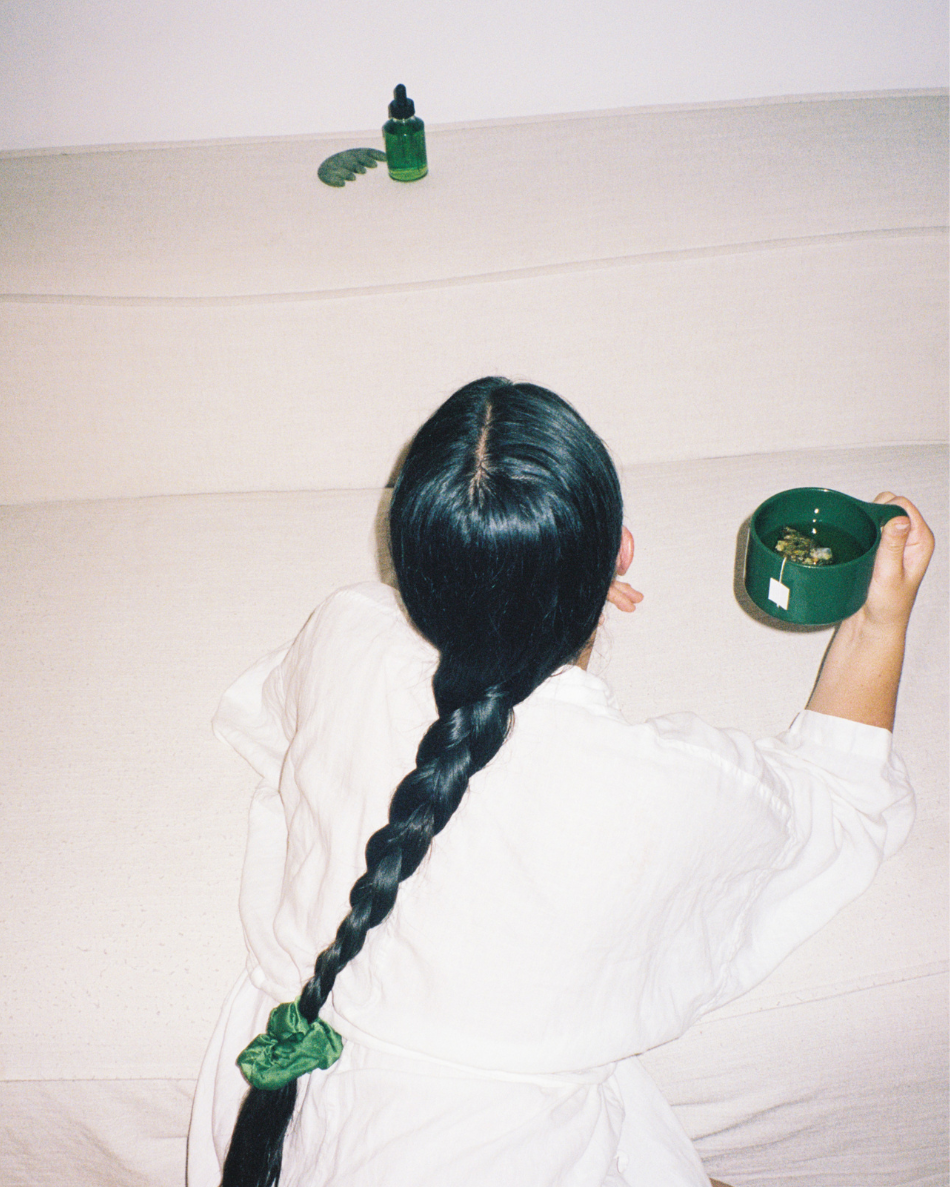 Rear view of a woman holding the Ritual Mug with her long hair braided