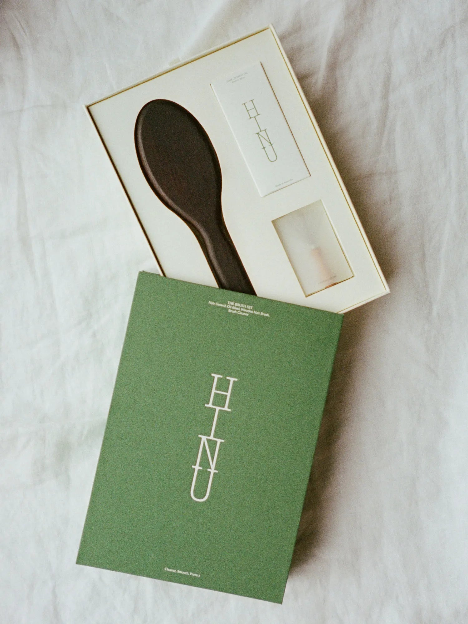 Open HINU Brush Gift Set in green packaging on white bedding