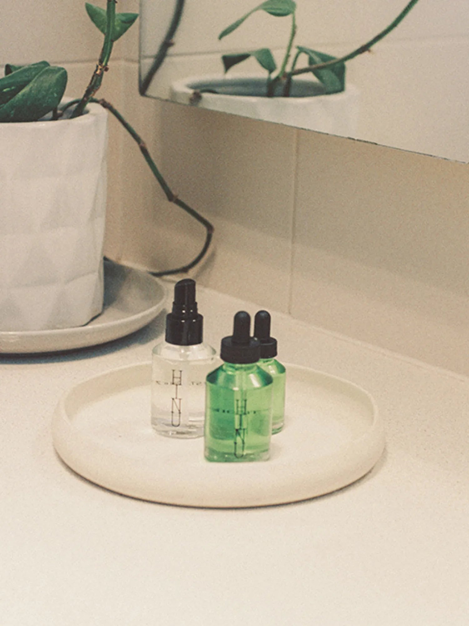 HINU Hair Growth Oil and Hydrating Mist arranged on a bathroom tray