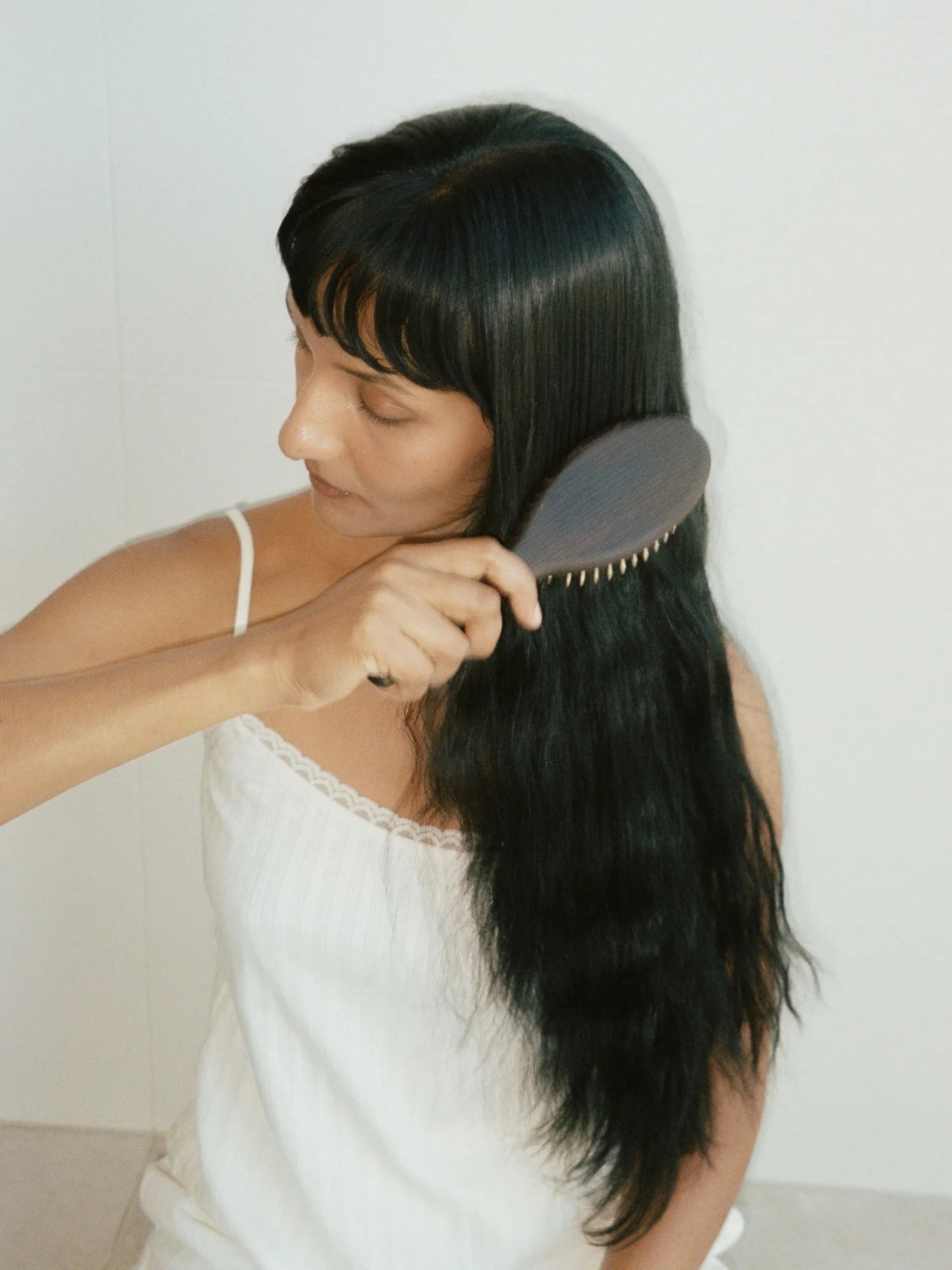 Woman brushing her long black hair with the HINU Wooden Hair Brush