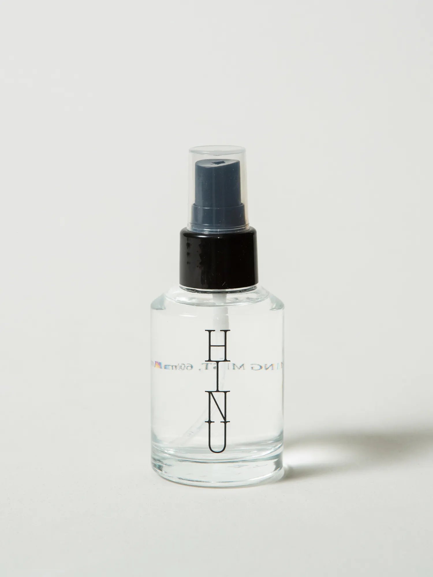 Clear HINU Hydrating Mist spray bottle on an off-white background