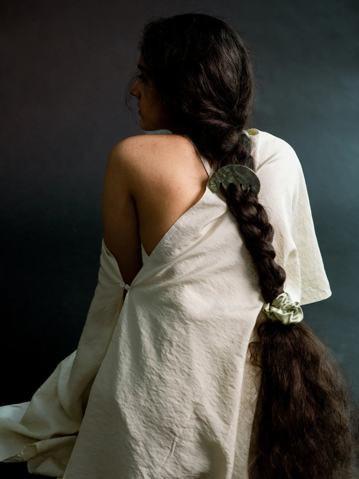 Woman with an extra-long braid secured by a light green HINU Silk Scrunchie
