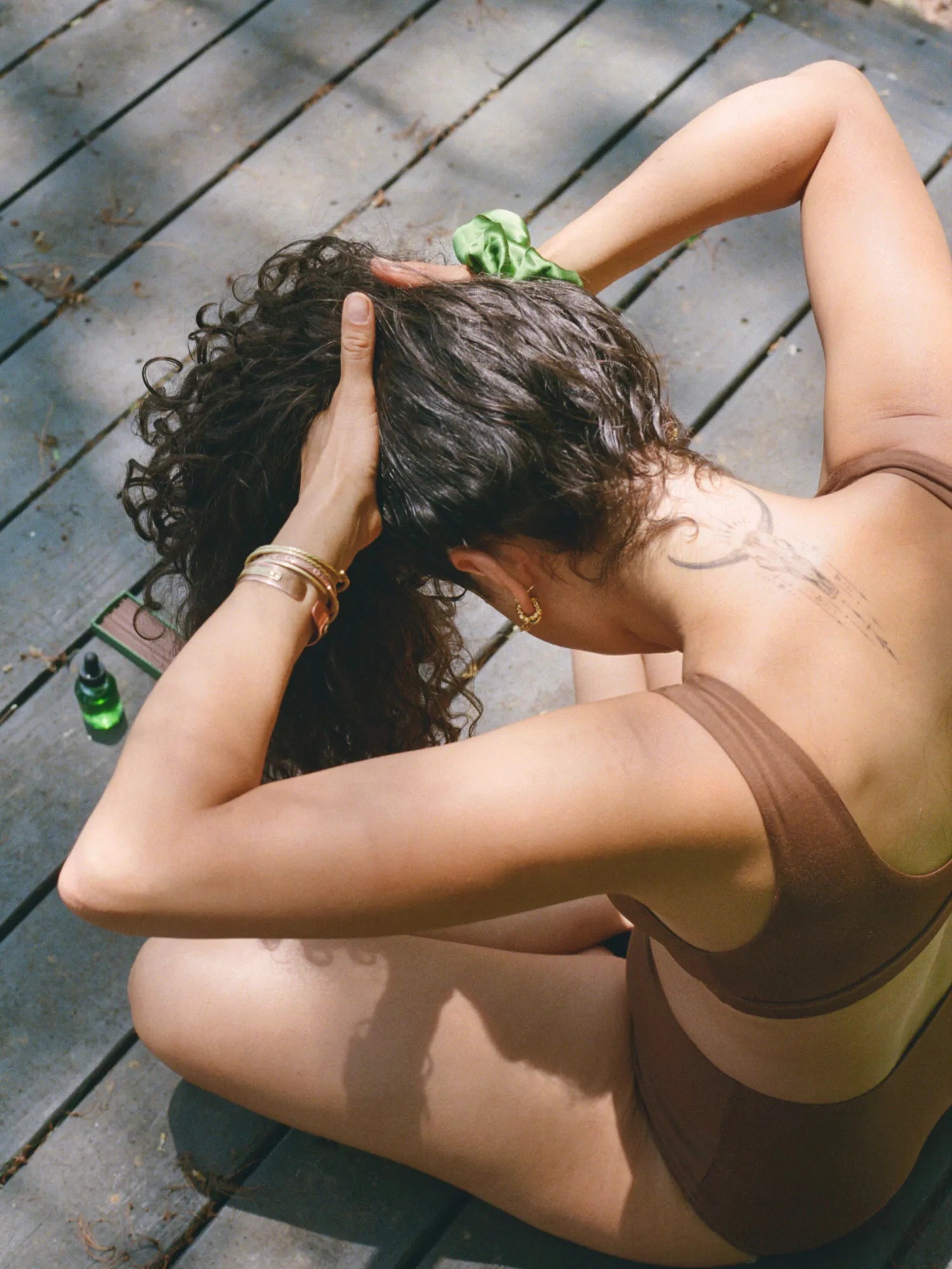Woman massaging HINU Hair Growth Oil into her curly hair outdoors