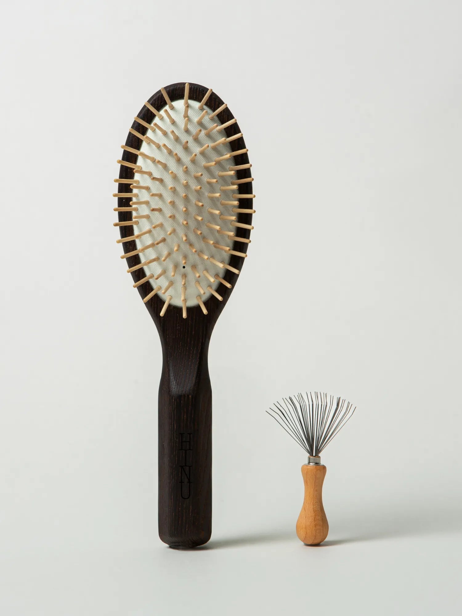 HINU Wooden Hair Brush and Hair Brush Cleaner standing on an off-white background