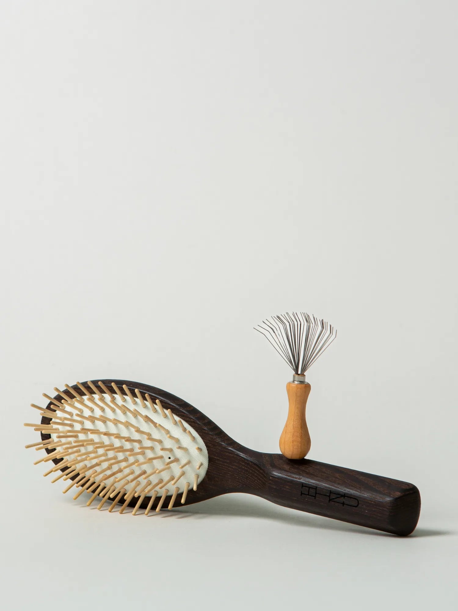 HINU Wooden Hair Brush and Hair Brush Cleaner arranged on an off-white background