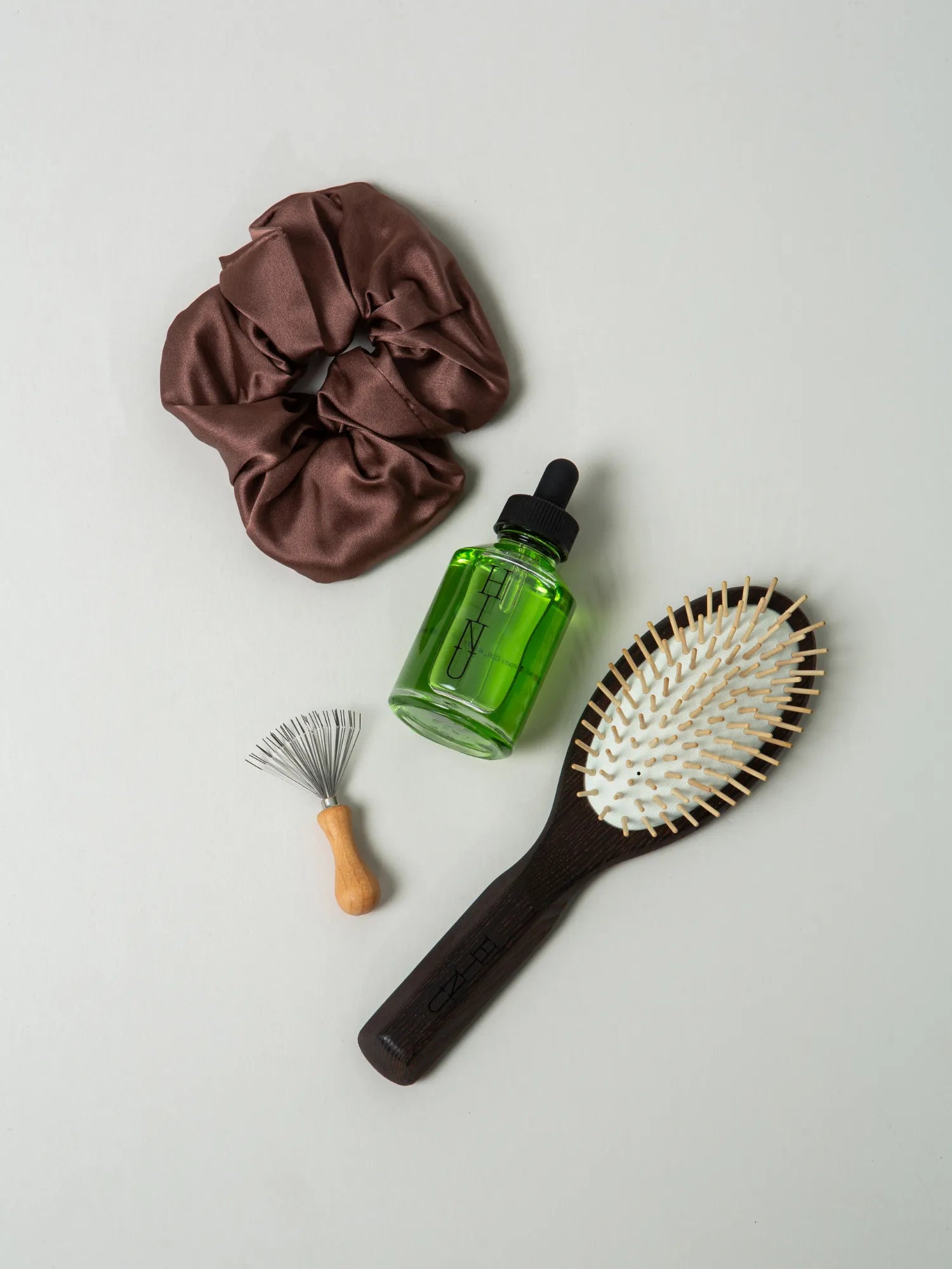 Overhead view of brown scrunchie, Hair Growth Oil, wooden brush and cleaner