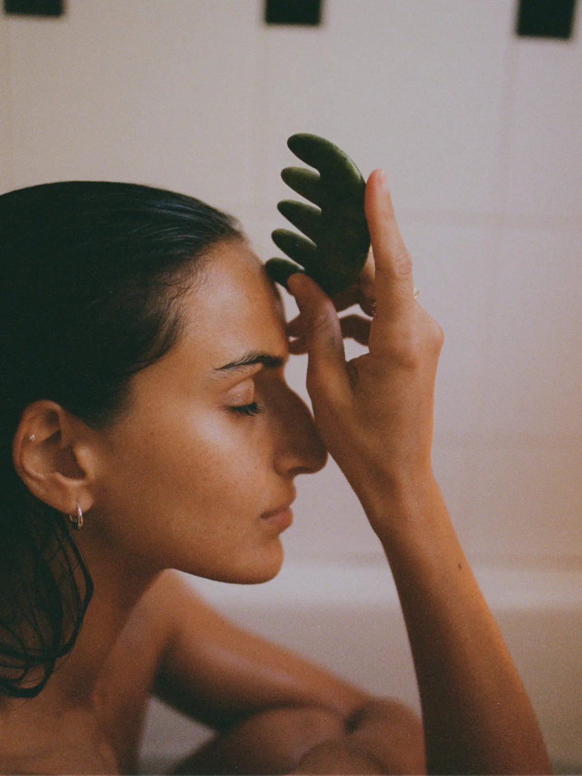 Woman gliding the HINU Jade Scalp Stimulator along her forehead