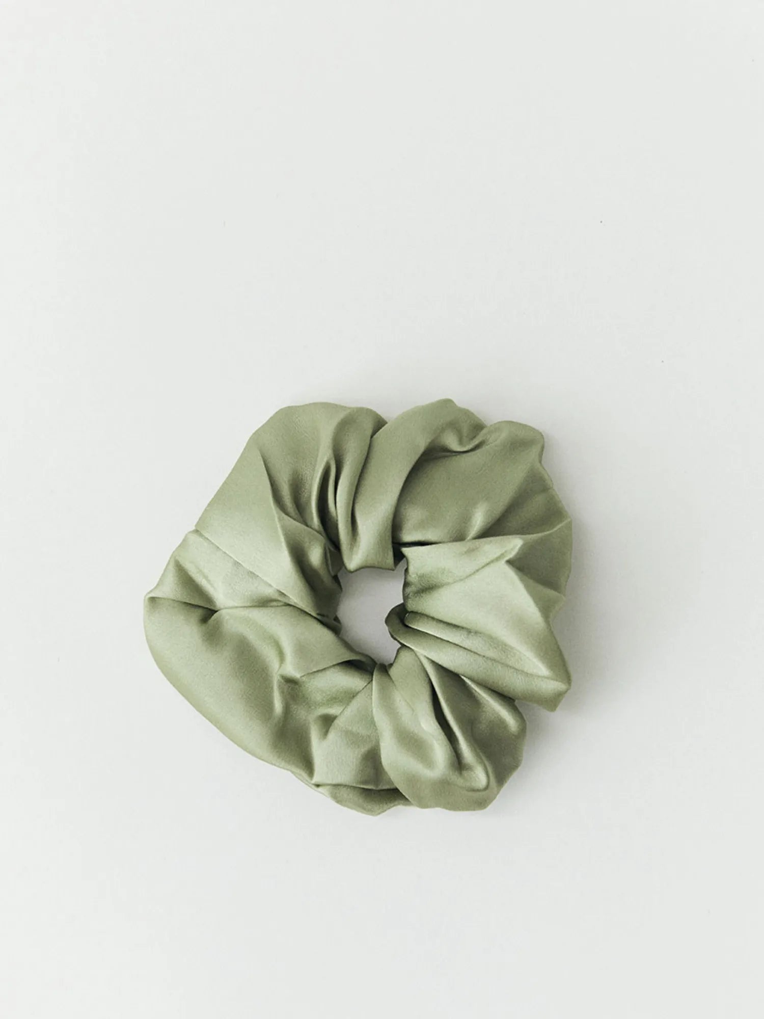 Light green HINU Silk Scrunchie on an off-white background