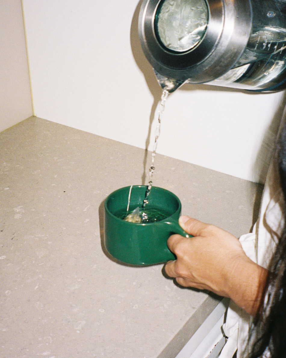 Person pouring hot water from a kettle into the green HINU Ritual Mug