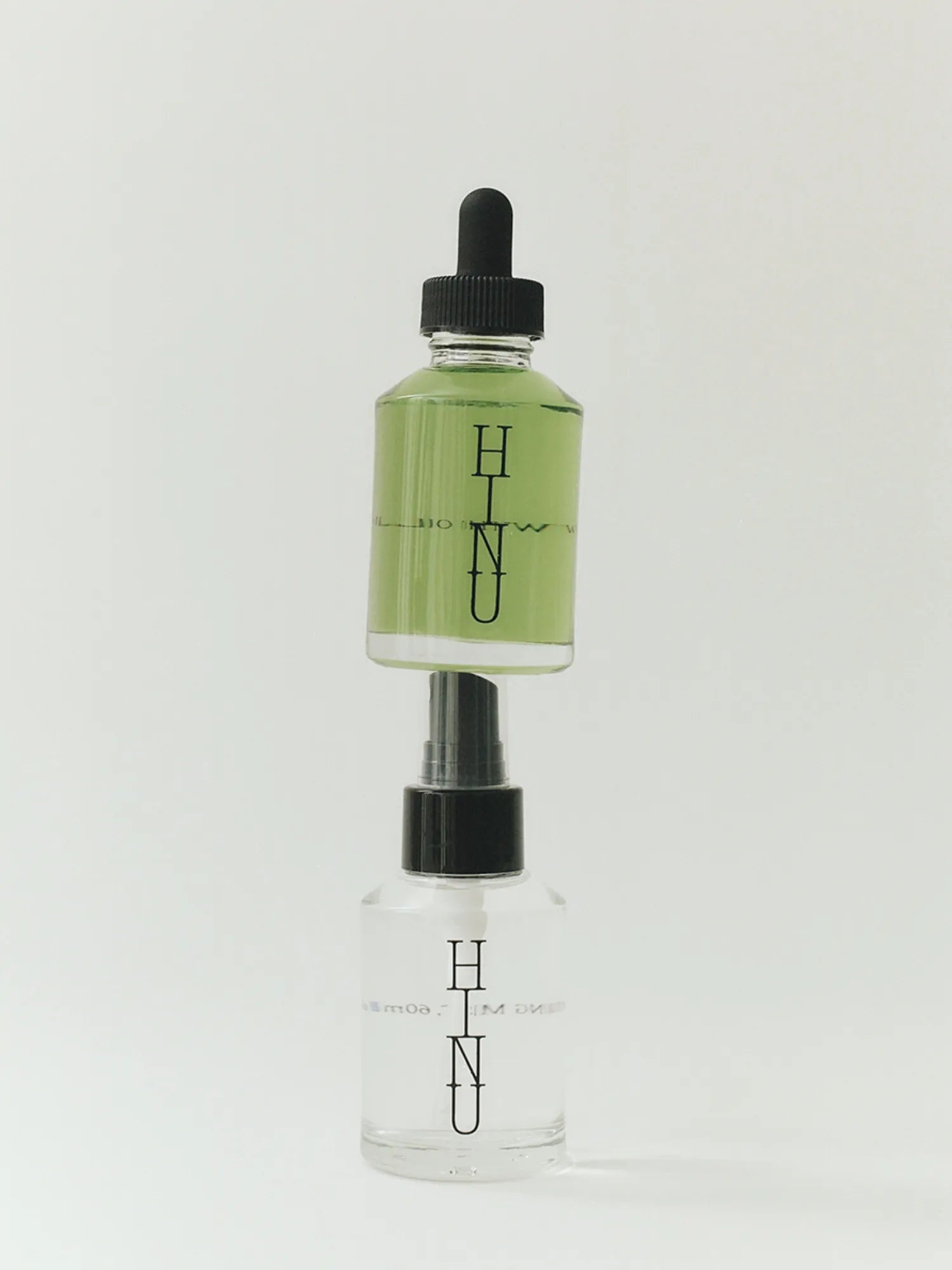 HINU Hair Growth Oil bottle stacked above the Hydrating Mist bottle