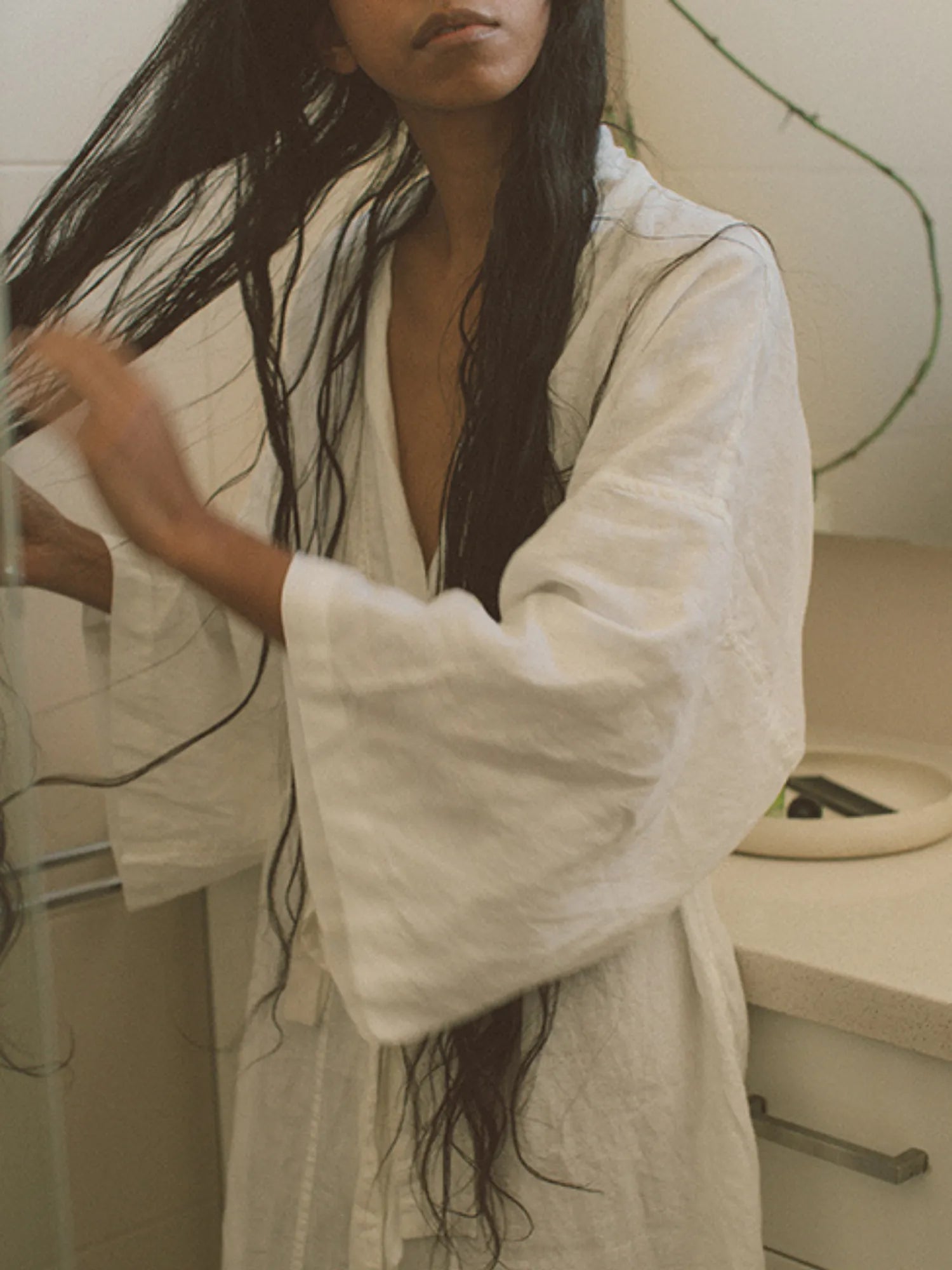Woman smoothing HINU Hydrating Mist through her long wet hair