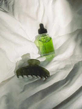 HINU Hair Growth Oil and Rimu Claw Clip arranged on white bedding