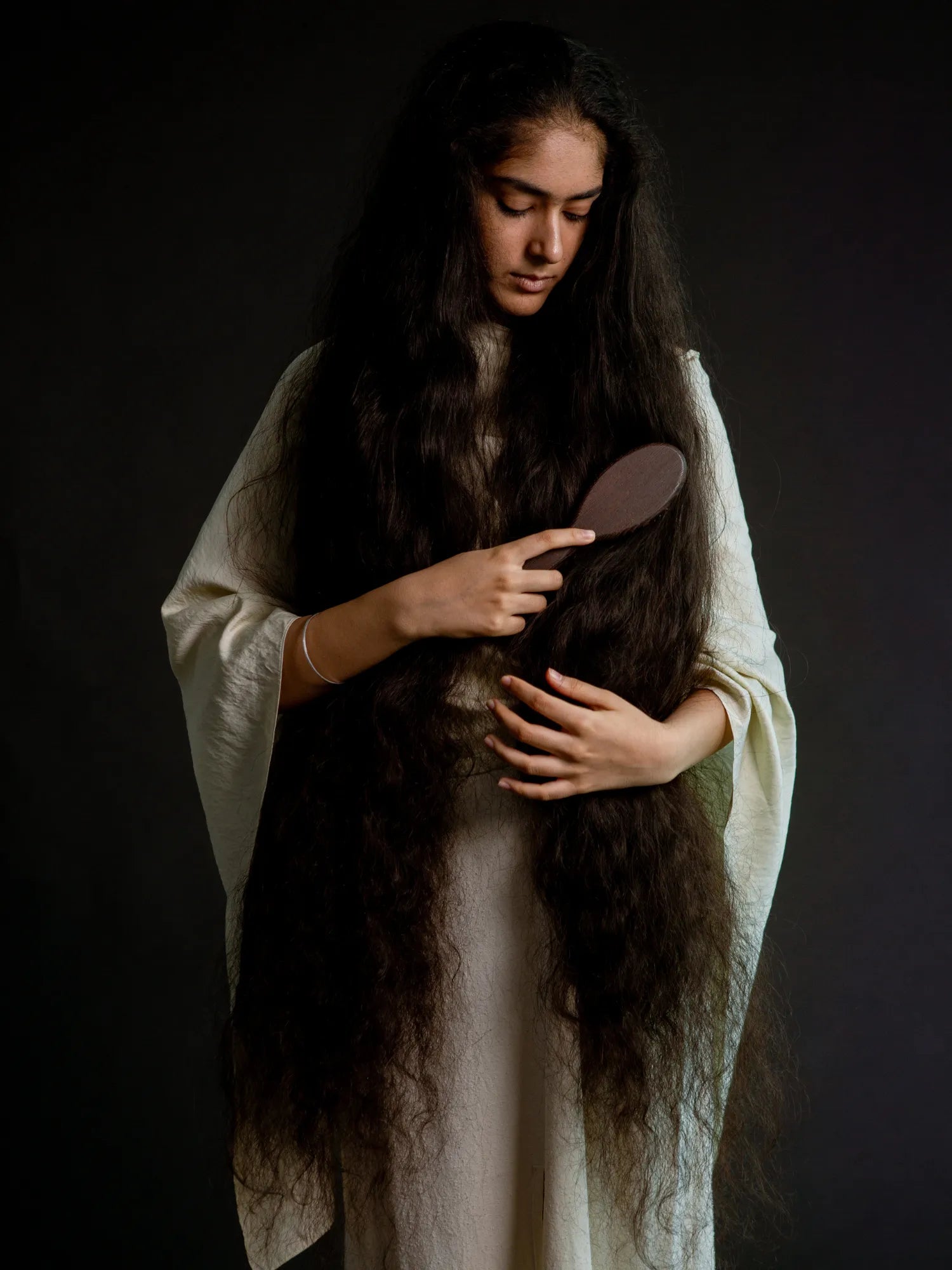Woman brushing her very long dark hair with the HINU Wooden Hair Brush