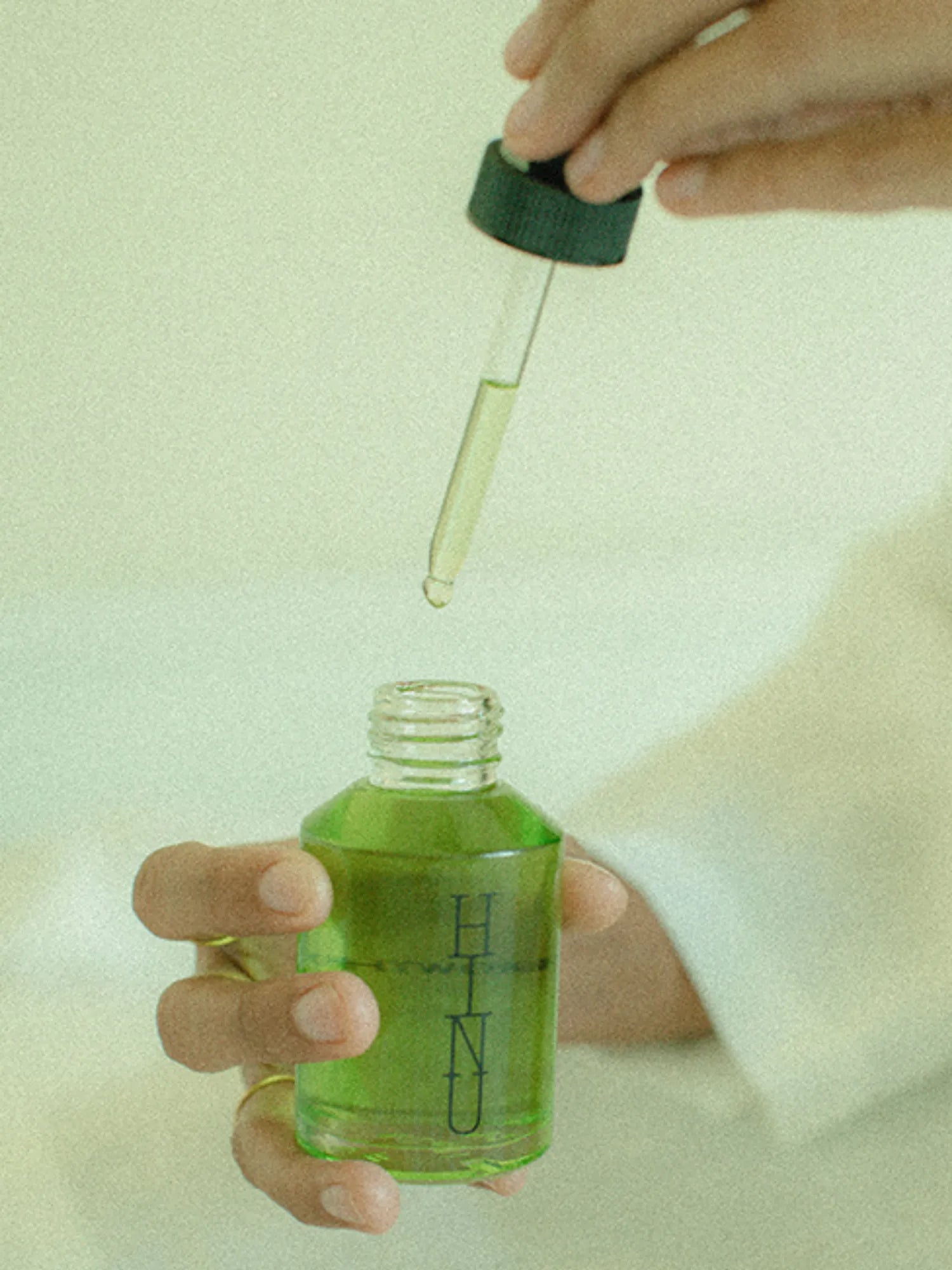 Close-up of a dropper held above an open bottle of HINU Hair Growth Oil
