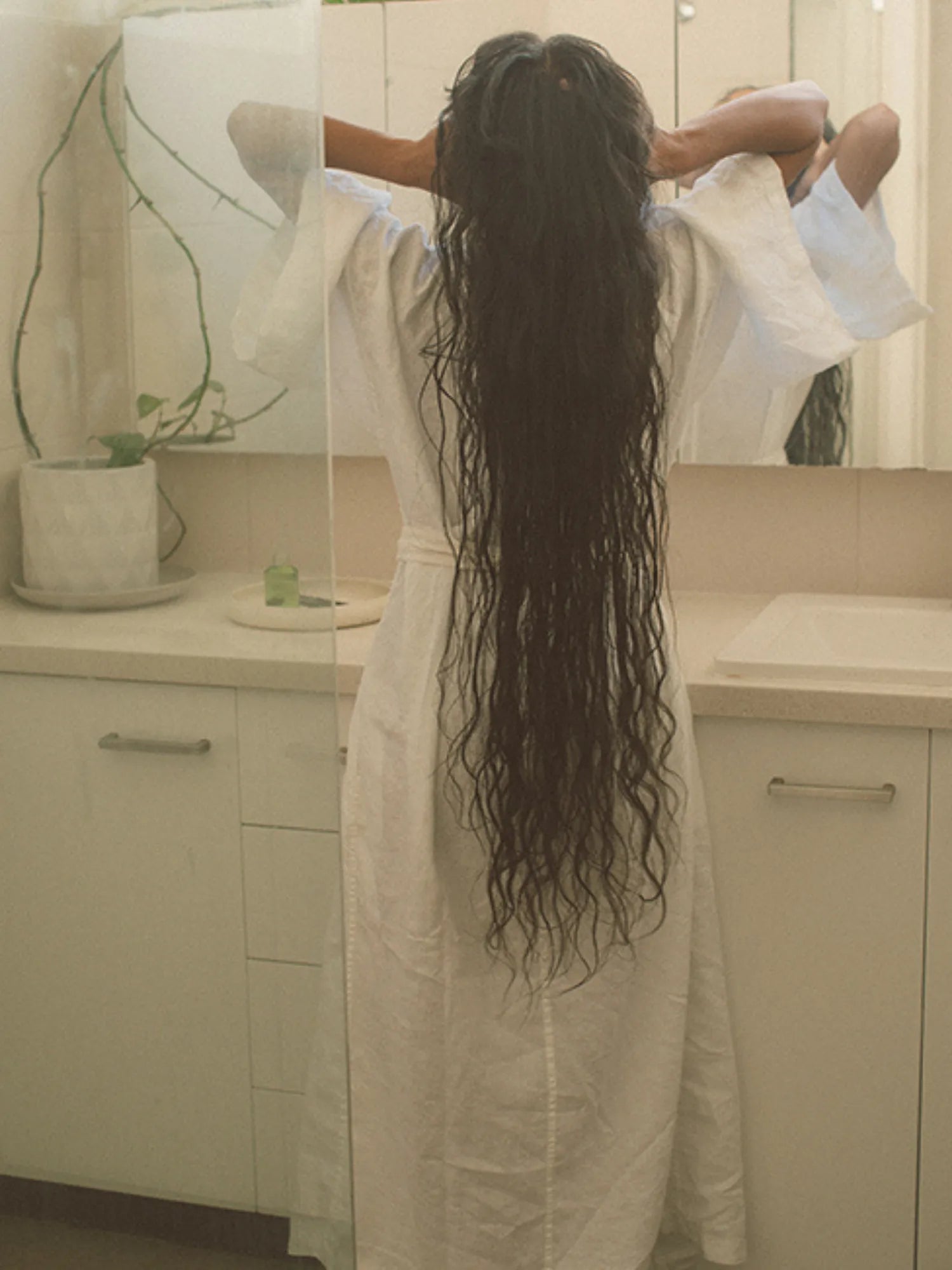 Rear view of a woman with very long wet hair standing in a bathroom