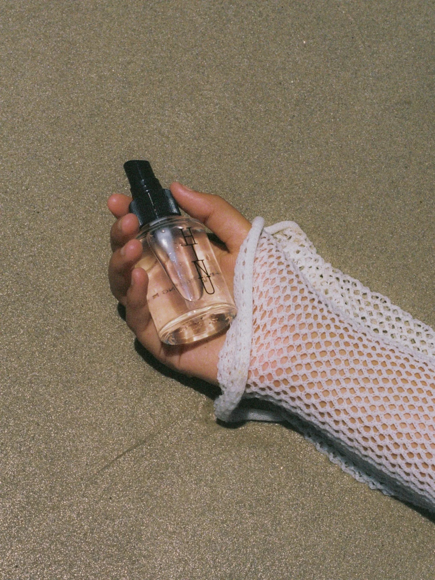 Hand holding a bottle of HINU Hydrating Mist outdoors