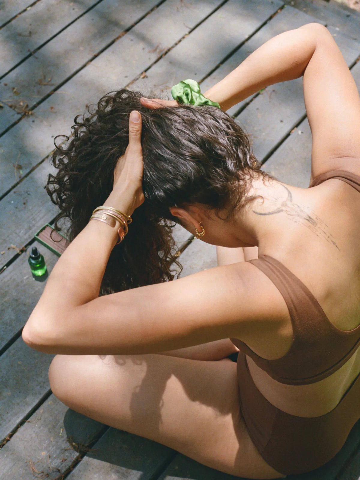 Woman massaging HINU Hair Growth Oil into her curly hair outdoors
