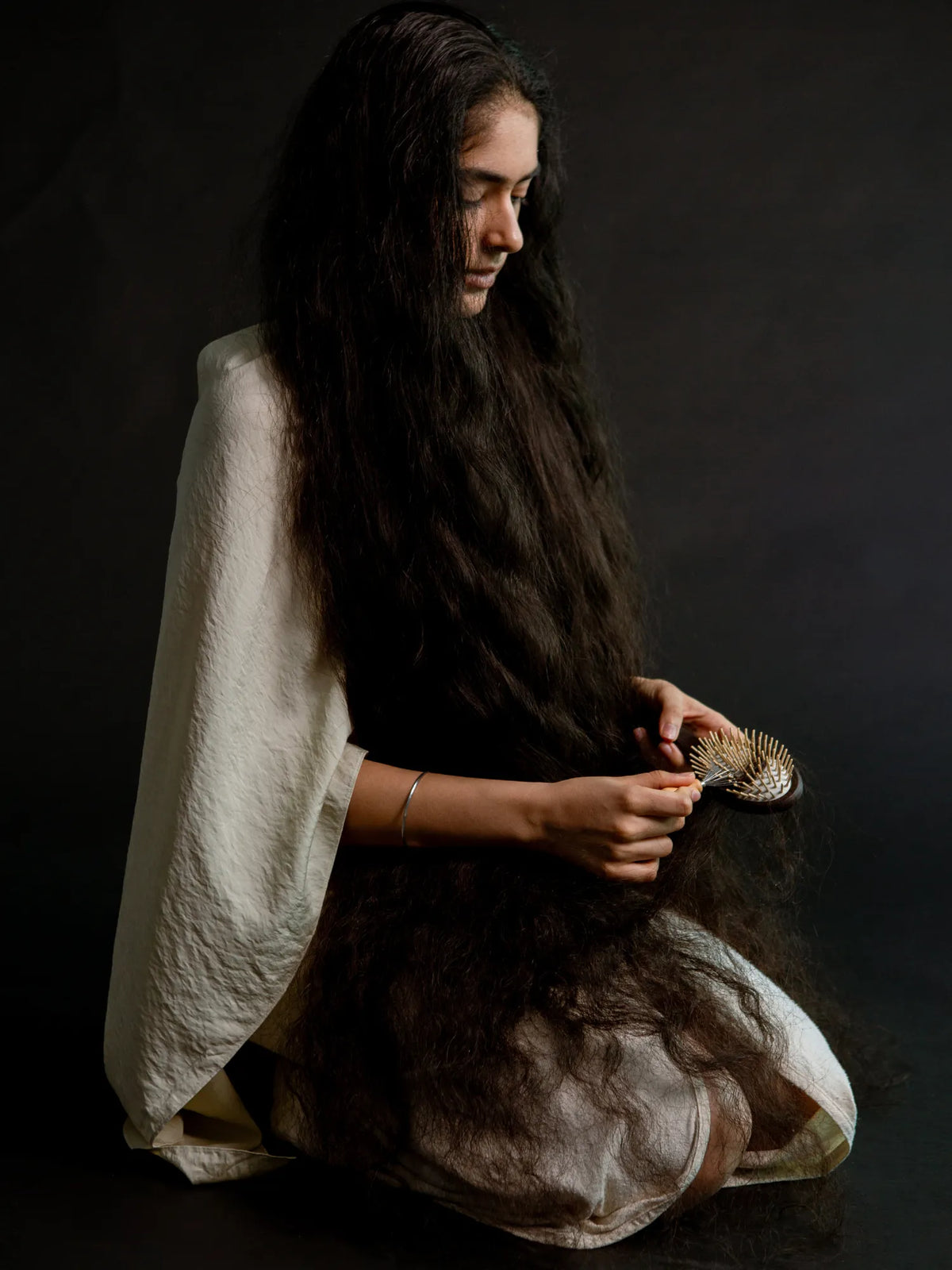 Woman holding the HINU Wooden Hair Brush over her very long hair