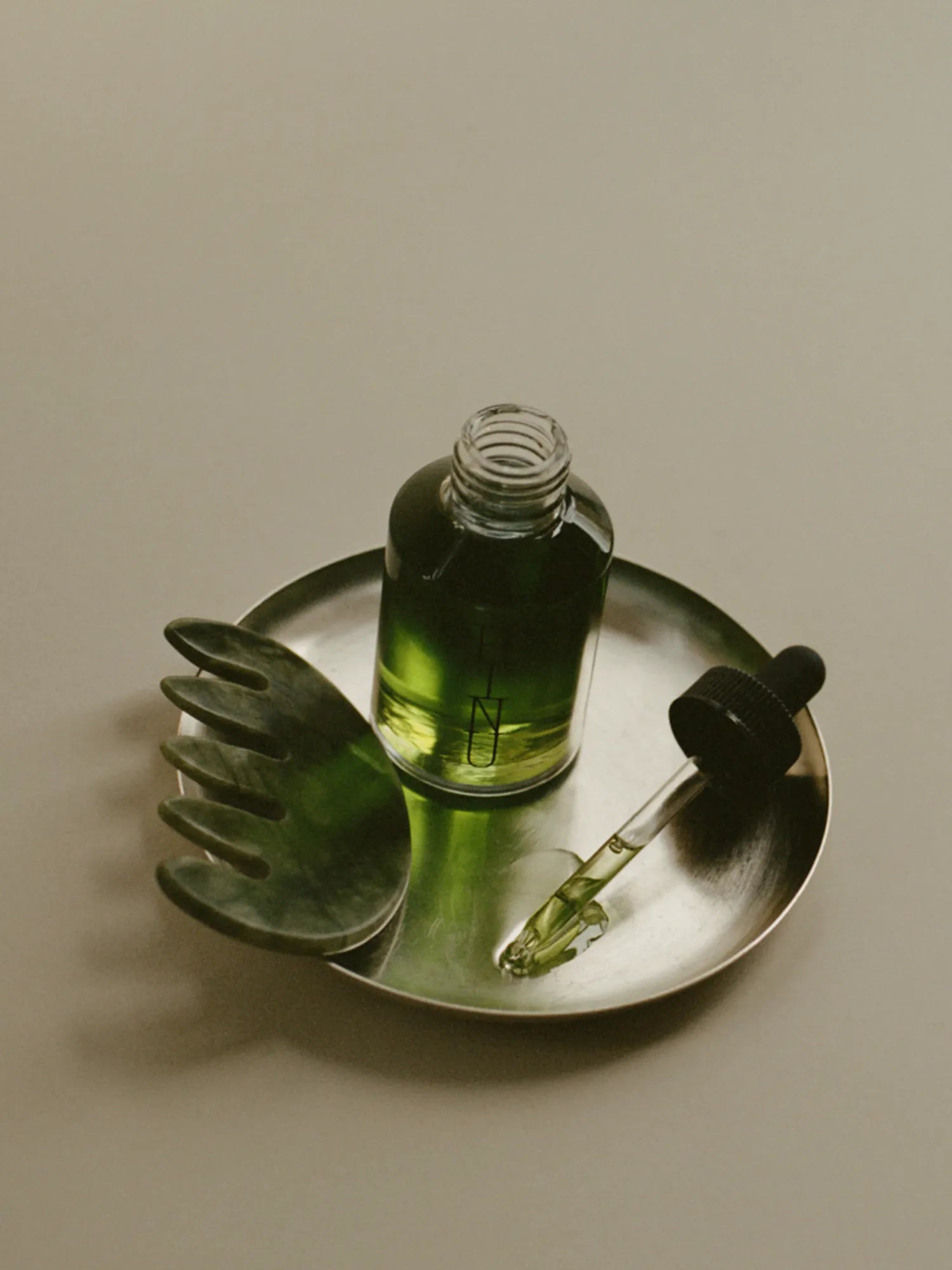 HINU Jade Scalp Stimulator and Hair Growth Oil arranged in a metal dish