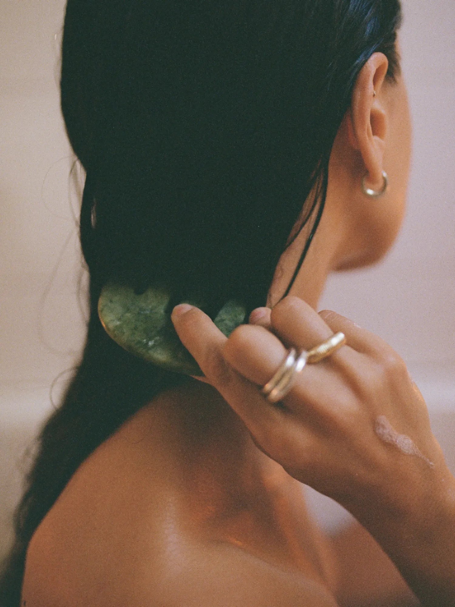 Woman massaging the back of her neck with the HINU Jade Scalp Stimulator