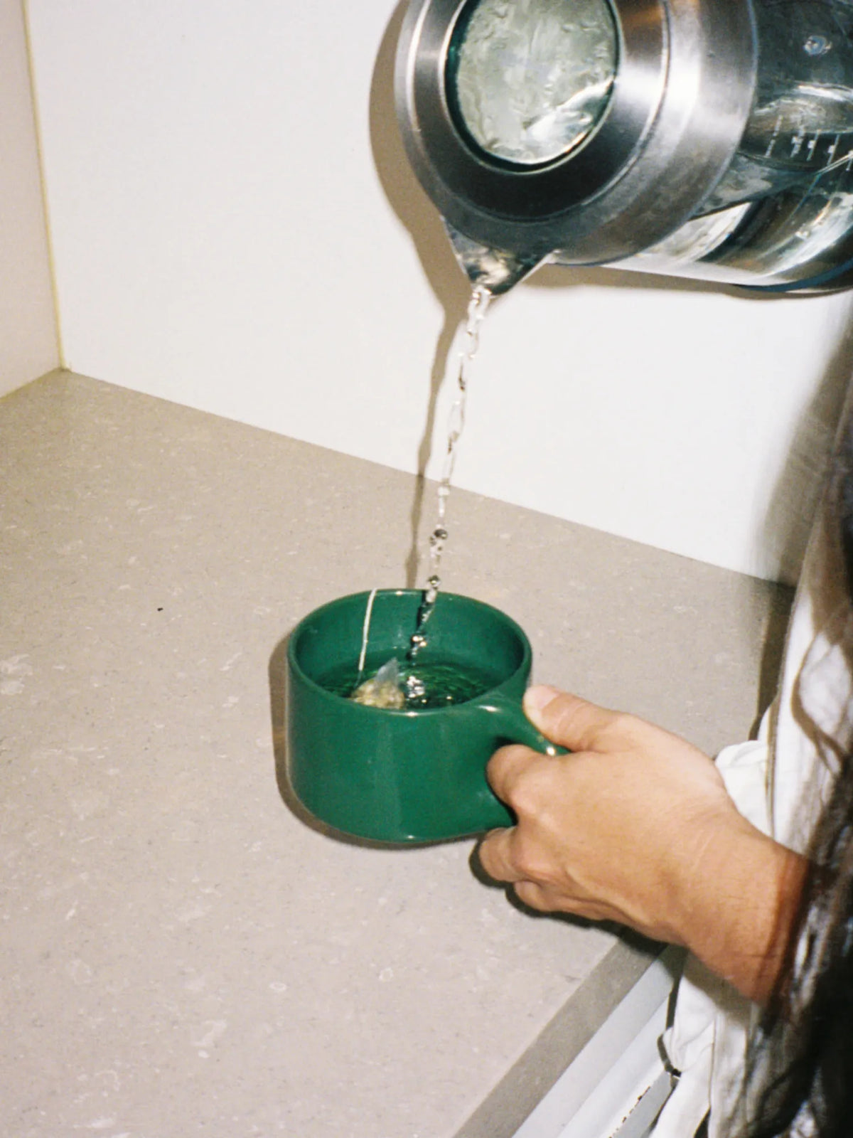 Person pouring hot water from a kettle into the green HINU Ritual Mug