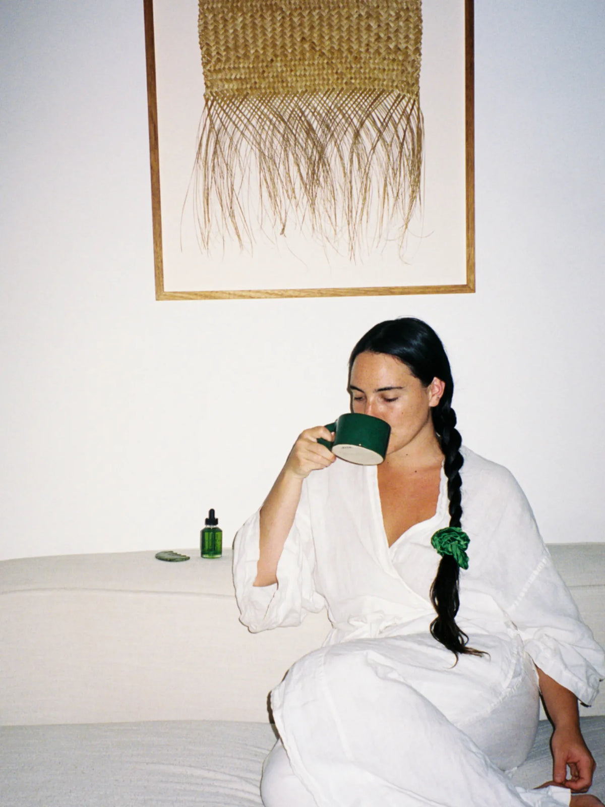 Woman in a white robe drinking from the green HINU Ritual Mug