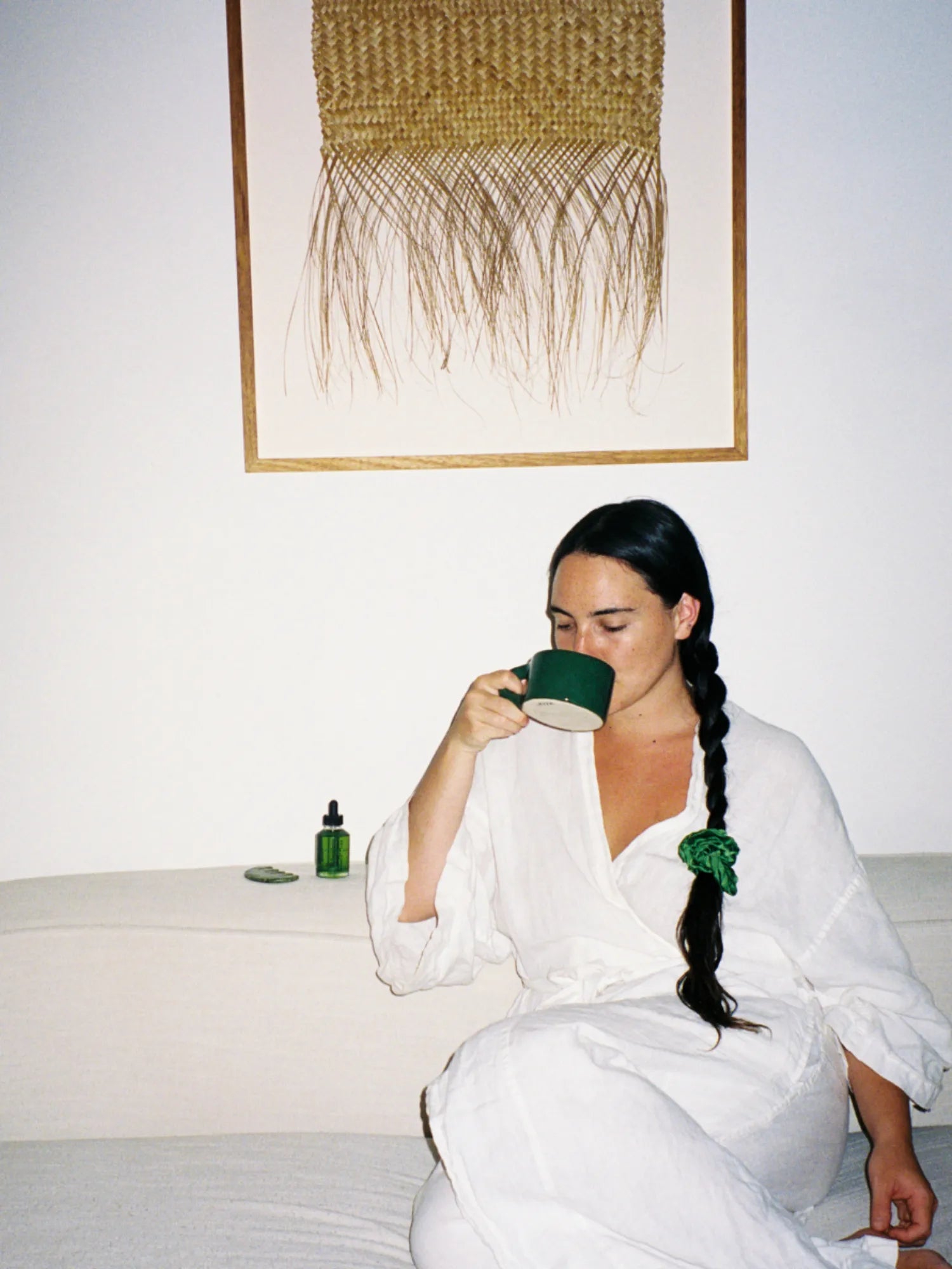 Woman in a white robe drinking from the green HINU Ritual Mug