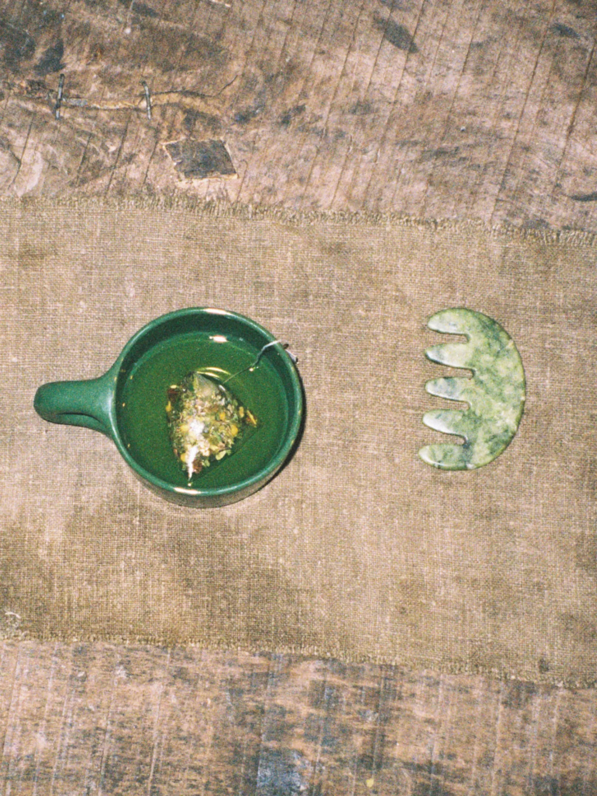 Green HINU Ritual Mug with tea beside a jade scalp tool