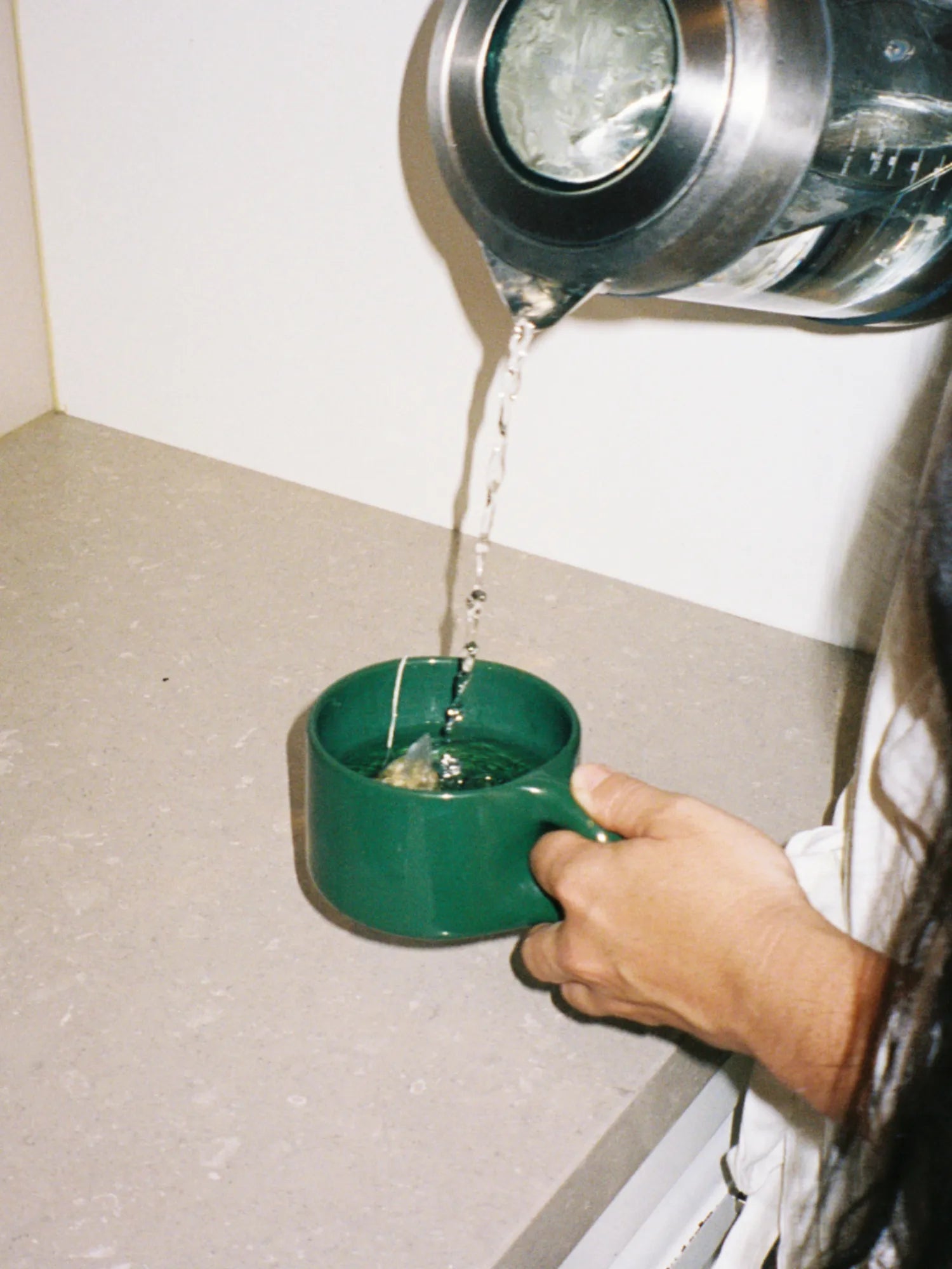Person pouring hot water from a kettle into the green HINU Ritual Mug