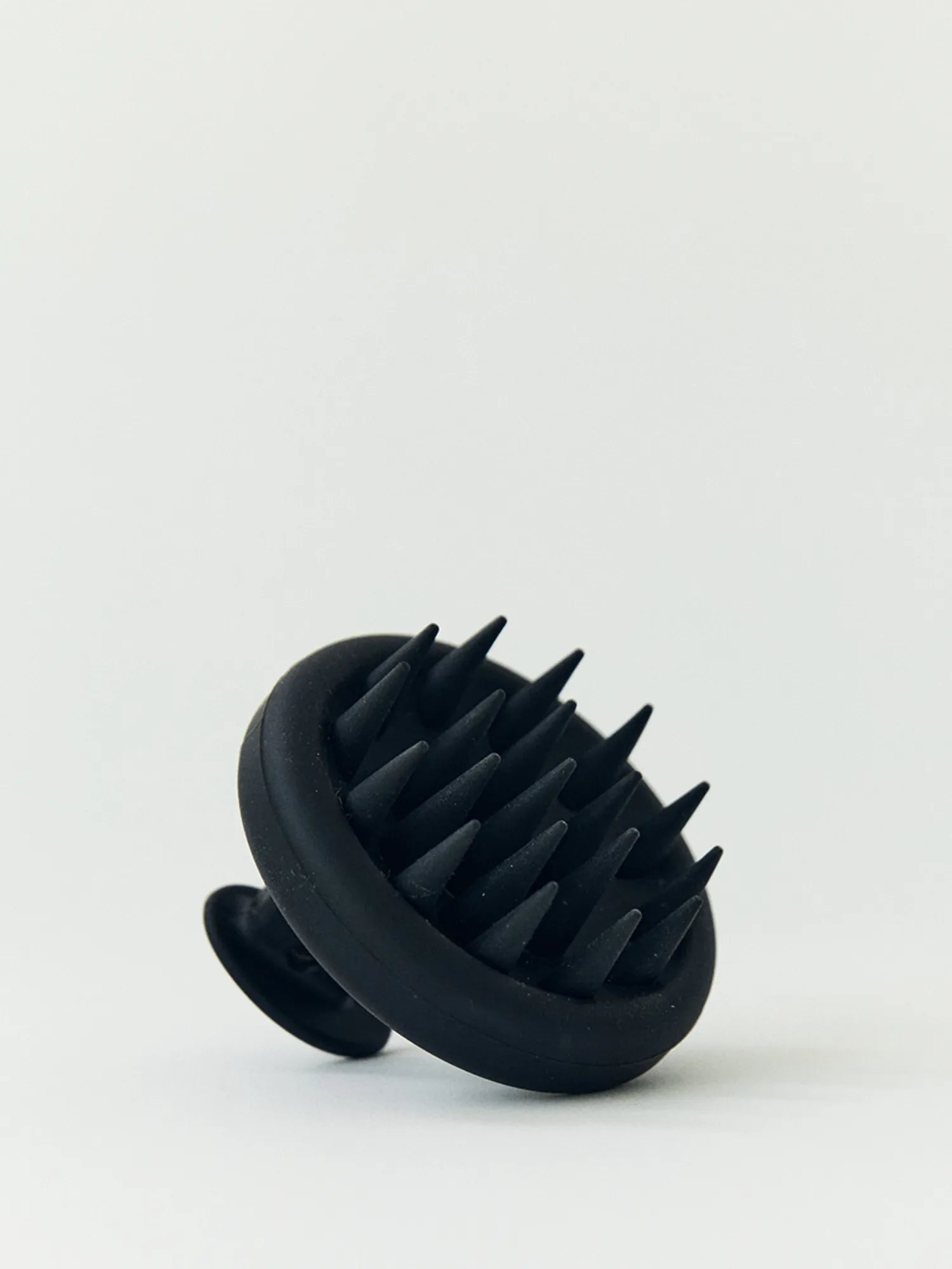 Close-up of the black HINU Scalp Massager showing its flexible bristles