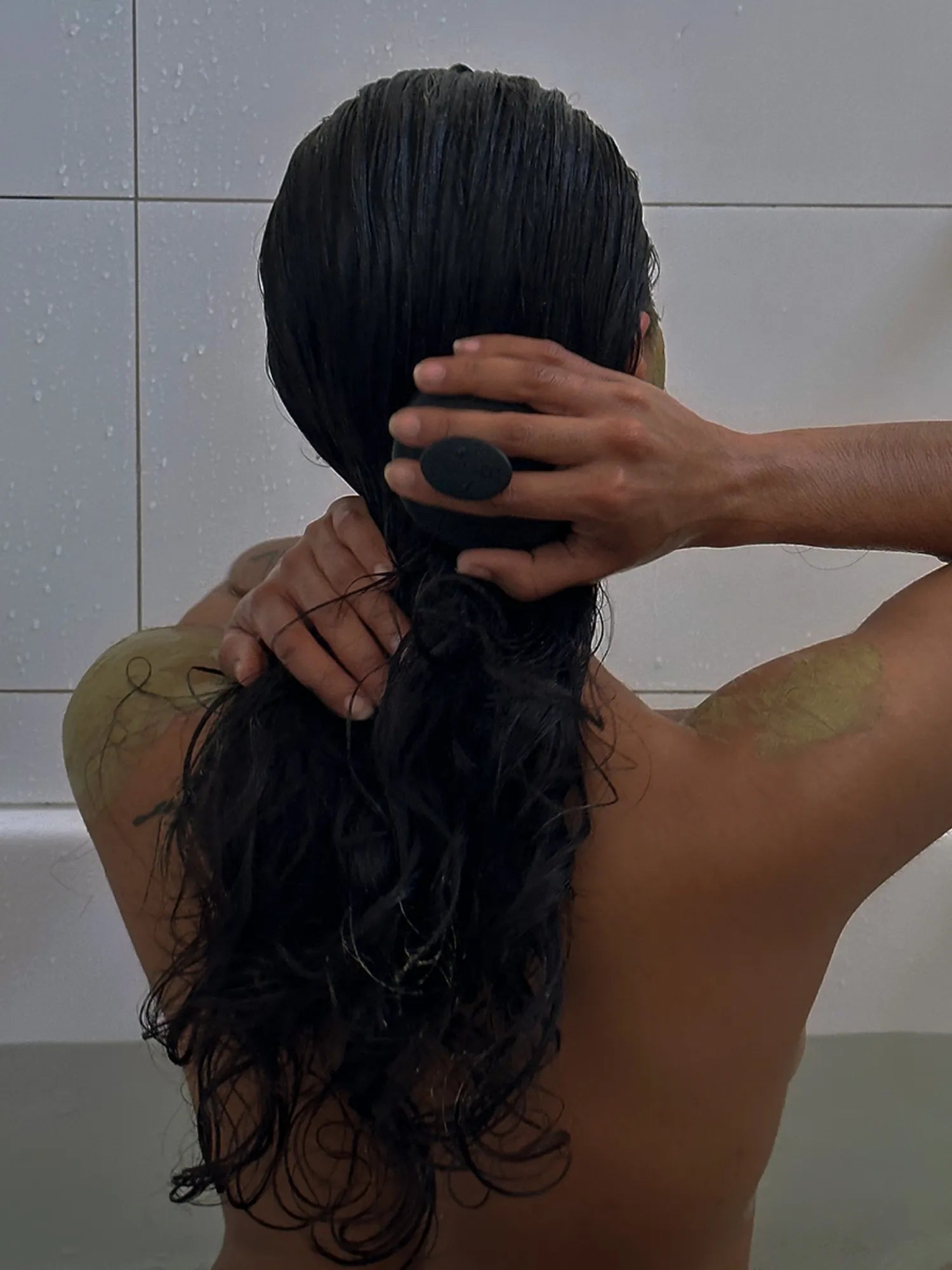 Woman massaging the back of her wet scalp with the HINU Scalp Massager