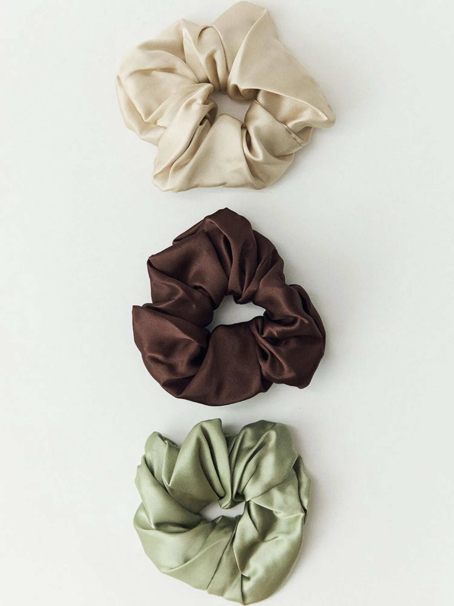 Three HINU Silk Scrunchies in oat, brown and light green